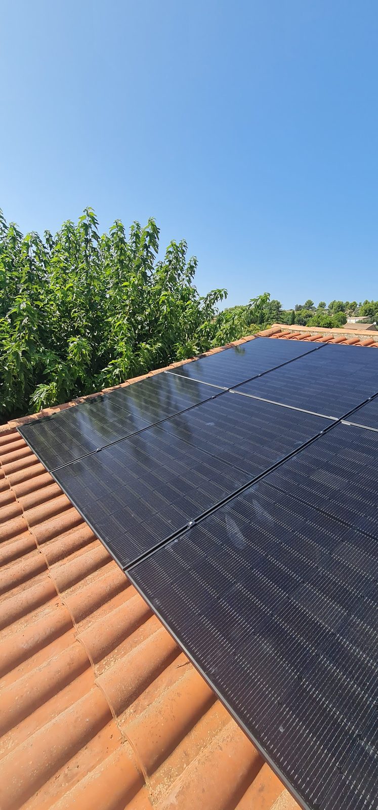 Champ de panneaux photovoltaïques vu depuis la toiture, installation ATSERV