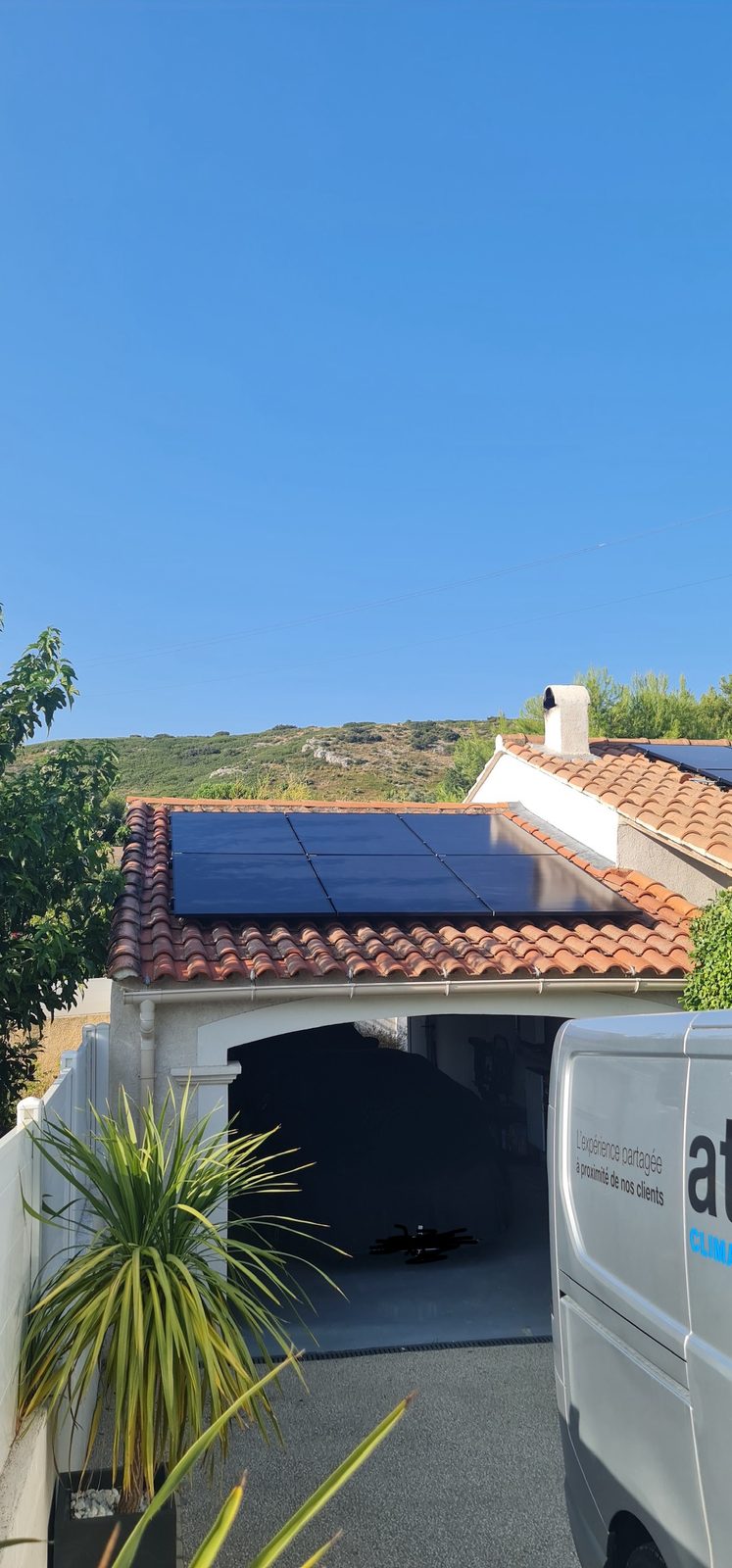 Panneaux solaires posés sur le toit d'un garage, fourgon ATSERV devant la maison